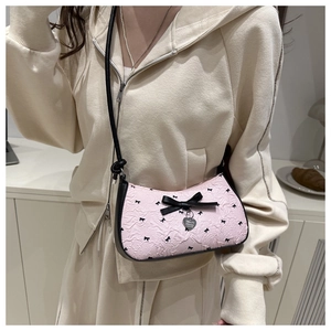 Close-up of pink crescent underarm bag with black bow prints and silver heart pendant