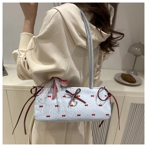 Detail of light blue shoulder bag featuring red bow patterns and a silver heart charm