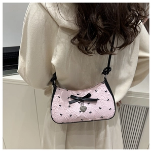 Détail du sac à bandoulière rose avec nœuds noirs et pendentif en forme de cœur argenté