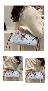 Detail view of light blue shoulder bag featuring red bows, white lace, and heart pendant