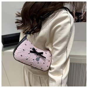 Detail of pink shoulder bag with black bow patterns and silver heart pendant charm