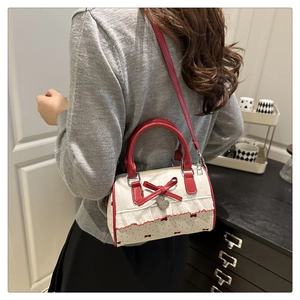 Rear view of a model wearing a bow-knot print shoulder bag with lace trim and red handles