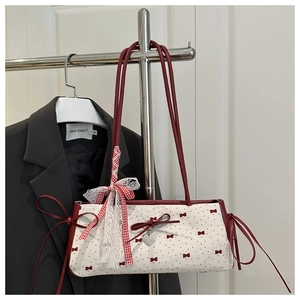 Detail of canvas shoulder bag with red bow prints, heart pendant and lace trim