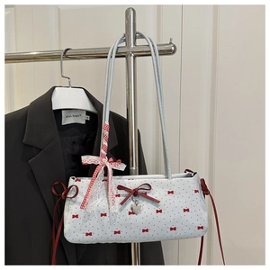 Detail of light blue baguette bag featuring red bow patterns and a silver heart pendant