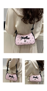 Détail du sac croissant rose avec motifs de nœuds noirs et pendentif cœur argenté