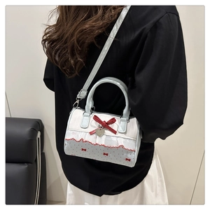 Close-up of light blue polka dot Boston bag with red bow and heart charm details