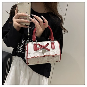 Close-up of a white polka dot barrel bag with red bow detail and ruffled edges