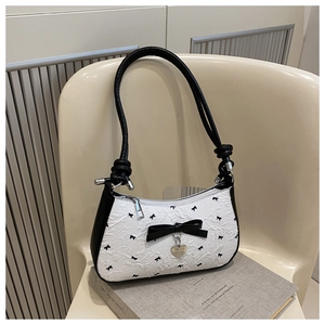 Détail du sac croissant plissé blanc avec nœuds noirs et pendentif en métal en forme de cœur