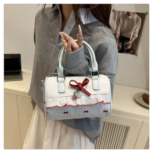 Close-up of blue cylinder bag featuring lace trim, red bows and silver heart charm