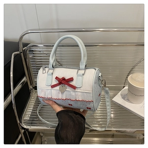 Detail of Boston barrel bag with red bow, lace trim and heart metal pendant