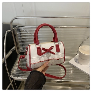 Detail of red and white polka dot Boston bag with bow, lace trim and heart charm