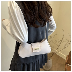 Detail of cream minimalist baguette bag with golden buckle shown on shoulder