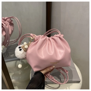 Detail of pink pleated bucket bag with plush monster charm and leather brand embossing