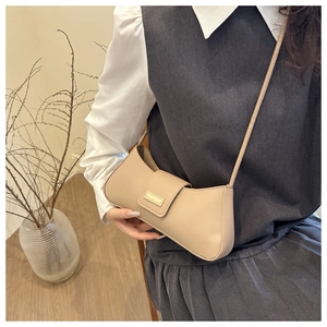 Détail du sac baguette en cuir beige minimaliste avec rabat et bandoulière fine assortie