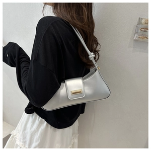 Sac sous le bras argenté avec boucle dorée et bandoulière nouée sur un mannequin femme