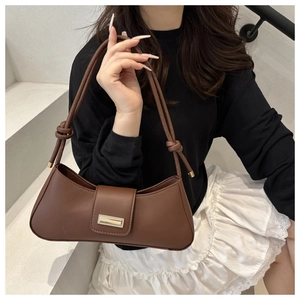 Detail of coffee brown leather underarm bag with knot strap and gold metal buckle