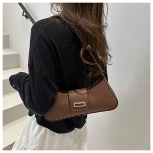 Brown faux leather baguette bag with gold metal buckle shown on model in minimal setting