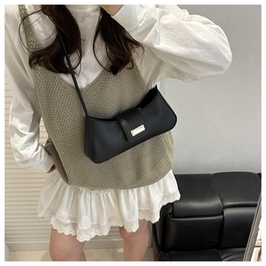 Détail d'un sac en cuir noir minimaliste avec une boucle dorée rectangulaire sur le rabat