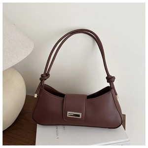 Détail du sac sous l'aisselle en cuir marron vintage avec boucle dorée et nœud