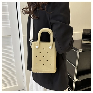Seitenansicht einer khakifarbenen EVA-Tasche mit Lochmuster und weißem Gurt am Model
