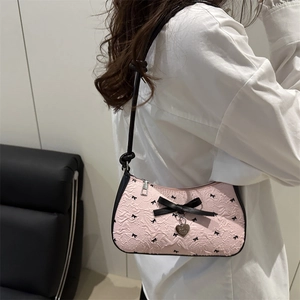 Sac croissant rose avec nœud noir et pendentif cœur sur un mannequin femme élégant
