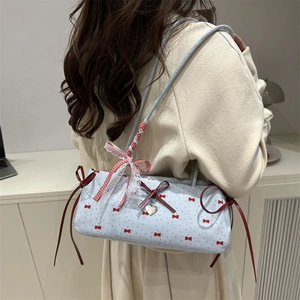 Blue rectangular shoulder bag with red bows and lace details shown on a model
