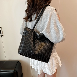 Black woven leather tote bag for women featuring long shoulder straps in a minimalist style