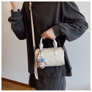Chic cream Boston bag with bear embossing and plush charm shown on a model