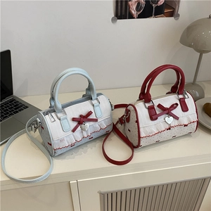 Bow cylinder handbag in blue and red featuring ruffled edges and heart pendant