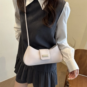 Sac sous le bras croissant crème chic avec boucle dorée sur un mannequin de style