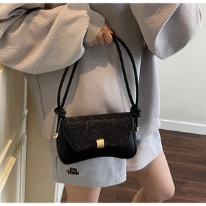 Détail du sac baguette noir avec rabat scintillant et boucle métallique dorée élégante