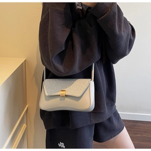 Détail du sac bandoulière gris avec rabat pailleté bleu dégradé et boucle dorée