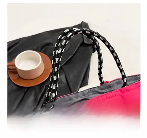 Detail view of pink nylon tote bag with black and white braided rope shoulder strap