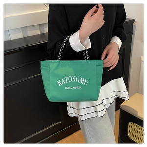 Close-up of vibrant green nylon tote bag with white lettering and braided rope handles