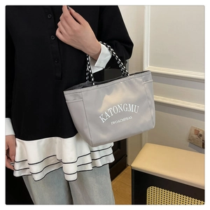 Detail of gray waterproof nylon tote bag featuring durable woven handles and white lettering