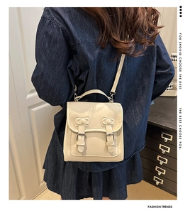 Détail du mini sac crème en cuir avec boucles et poignée porté par un mannequin
