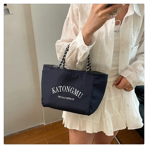 Detail view of navy blue tote bag with white lettering and woven striped handles