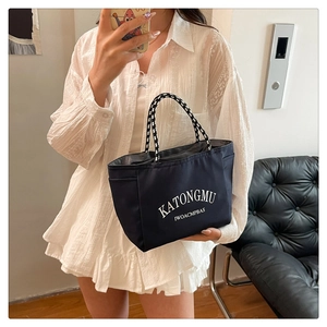 Close-up of navy nylon tote bag with white lettering and woven rope handles