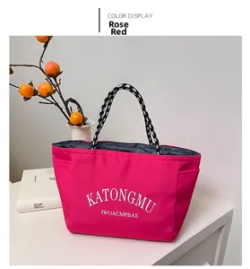 Detail of rose red tote bag with woven rope handles and printed white lettering