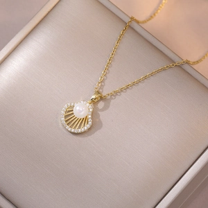 Detailed macro view of a gold ginkgo leaf necklace with zircon shell and pearl pendant