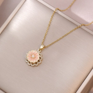 Collier marguerite dorée avec émail rose et perle sur une boîte à bijoux champagne