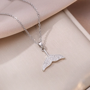 Elegant silver fish tail necklace with sparkling zircon pavé on champagne silk background