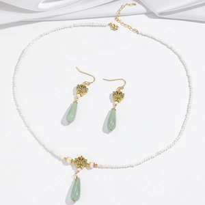 Elegant butterfly jewelry set with natural pearls and green stone pendant on white silk