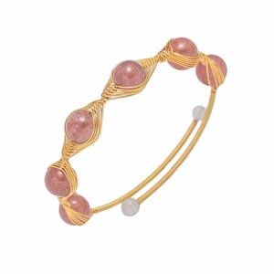 Detail of handmade gold wire-wrapped bracelet with pink strawberry quartz and pearl accents
