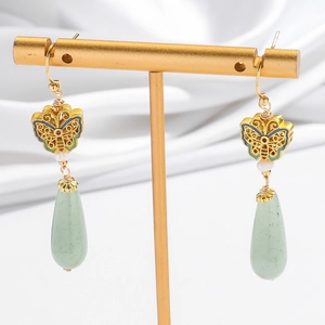 Detail of vintage gold butterfly earrings with natural green jade and pearl drops