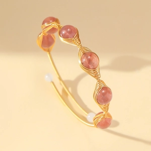 Macro detail of handmade wire-wrapped bracelet with strawberry quartz and natural pearls