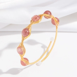 Detail of handmade gold wire-wrapped bangle featuring pink strawberry quartz beads