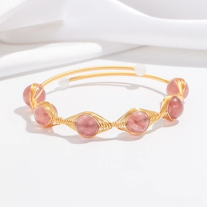 Detail of handcrafted gold wire wrapped bracelet with strawberry quartz and pearls