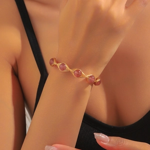 Detailed shot of handmade gold wire wrap bracelet with strawberry quartz beads