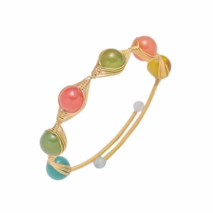 Detail of handcrafted gold wire wrapped open bangle with colorful strawberry crystal beads